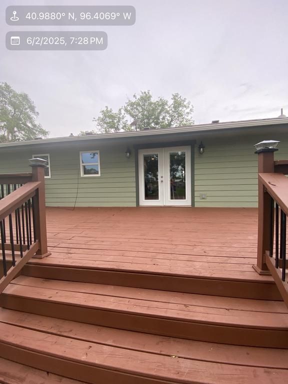 A wooden deck with stairs leading up to a green house