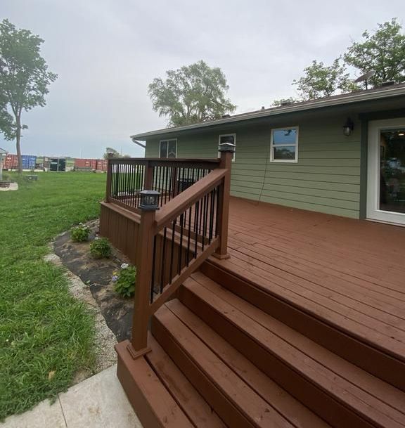 A green house with a wooden deck and stairs