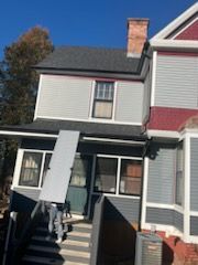 A man is carrying a large piece of furniture into a house.