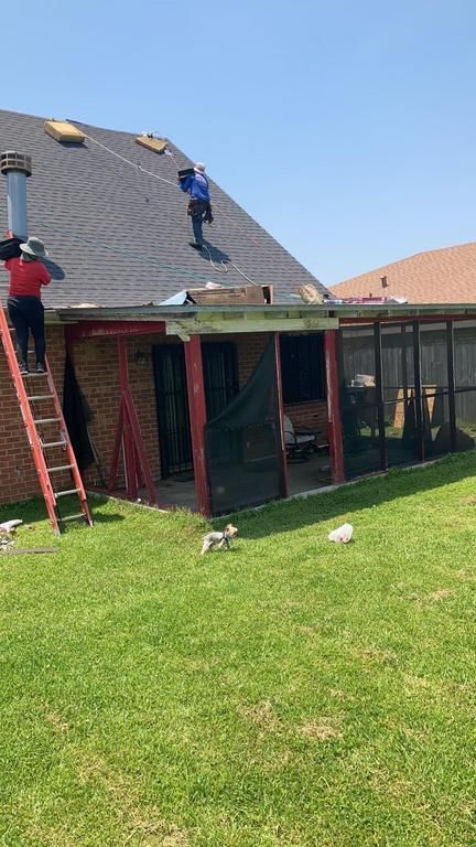 A man on a ladder is working on the roof of a house.
