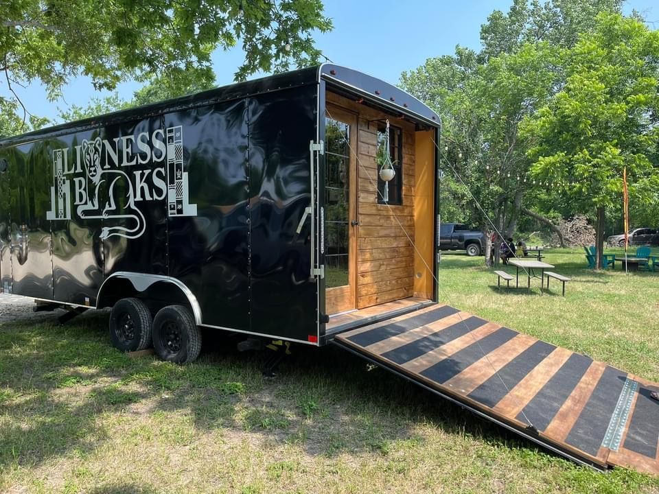 Black food trailer with open door and ramp, logo reads 