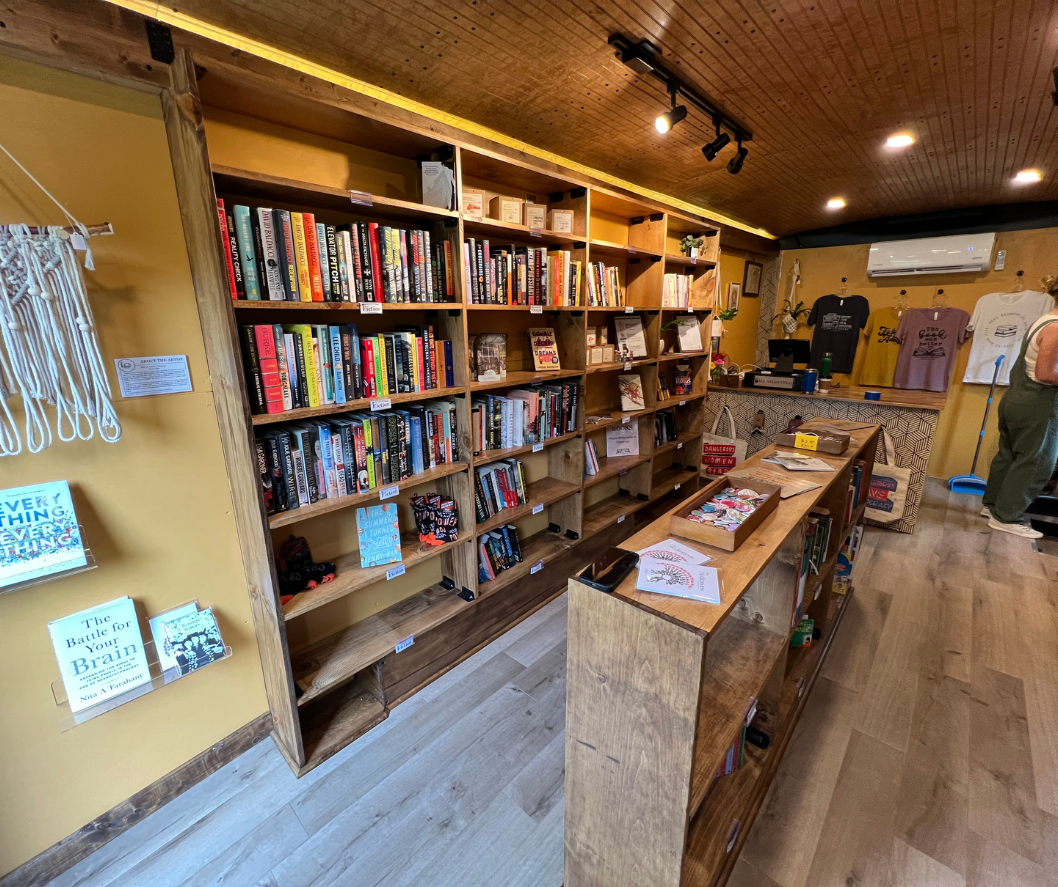 Bookshelves filled with books in a bookstore with wooden fixtures and yellow walls.