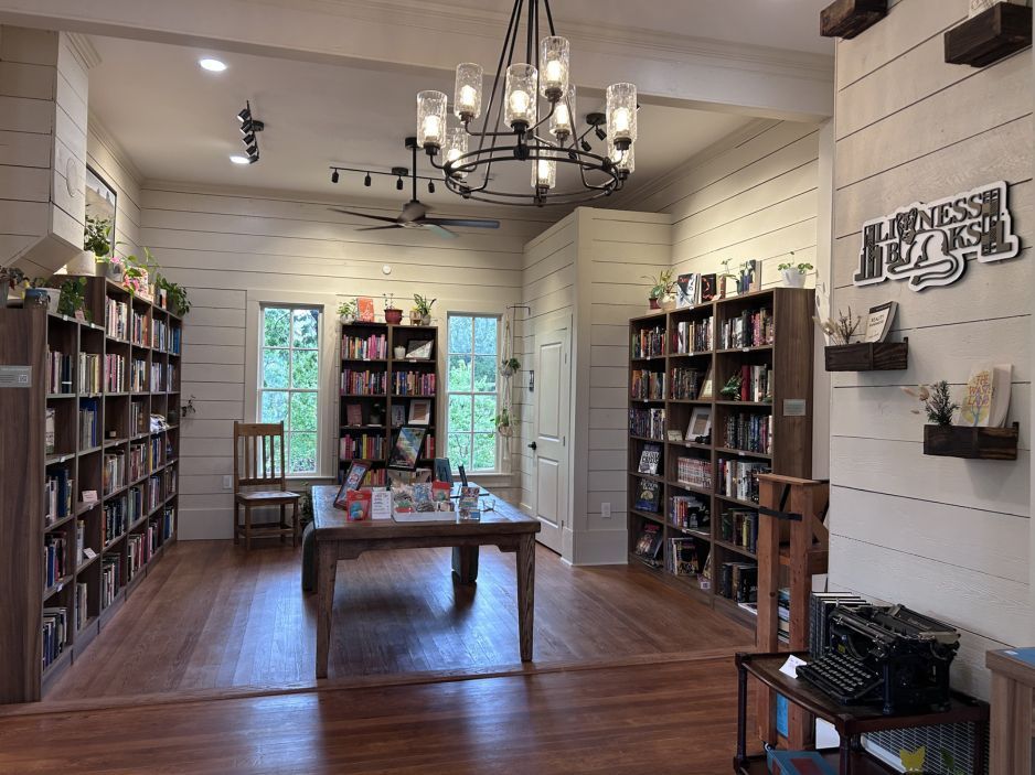 Cozy bookstore interior with bookshelves, wooden table, chandelier, and tall windows