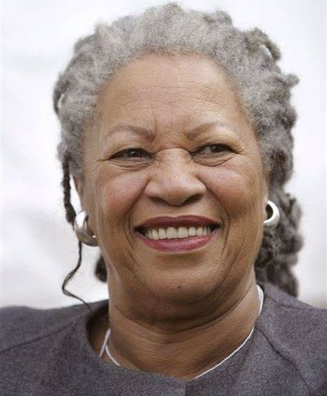 Smiling woman with gray hair in a bun wearing a gray top and hoop earrings.