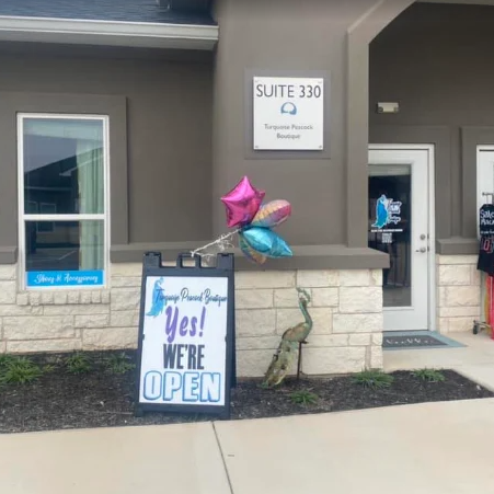 Storefront entrance with “Yes! We’re Open” sign and pink, blue balloons by Suite 330 door.