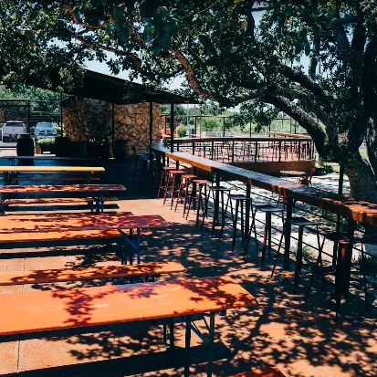 Nighttime outdoor restaurant patio with string lights, trees, and seated diners behind glass walls.