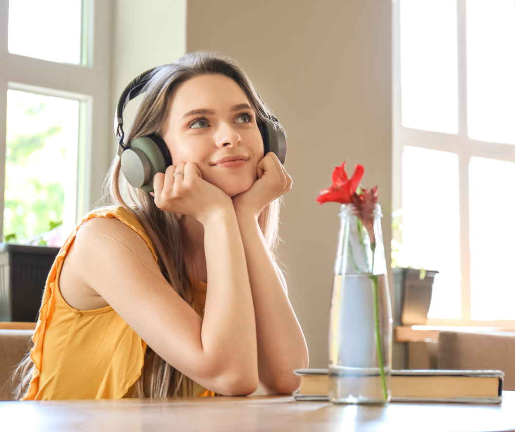 woman wearing headphones, presumably listening to music; she is situated in a well-lit room