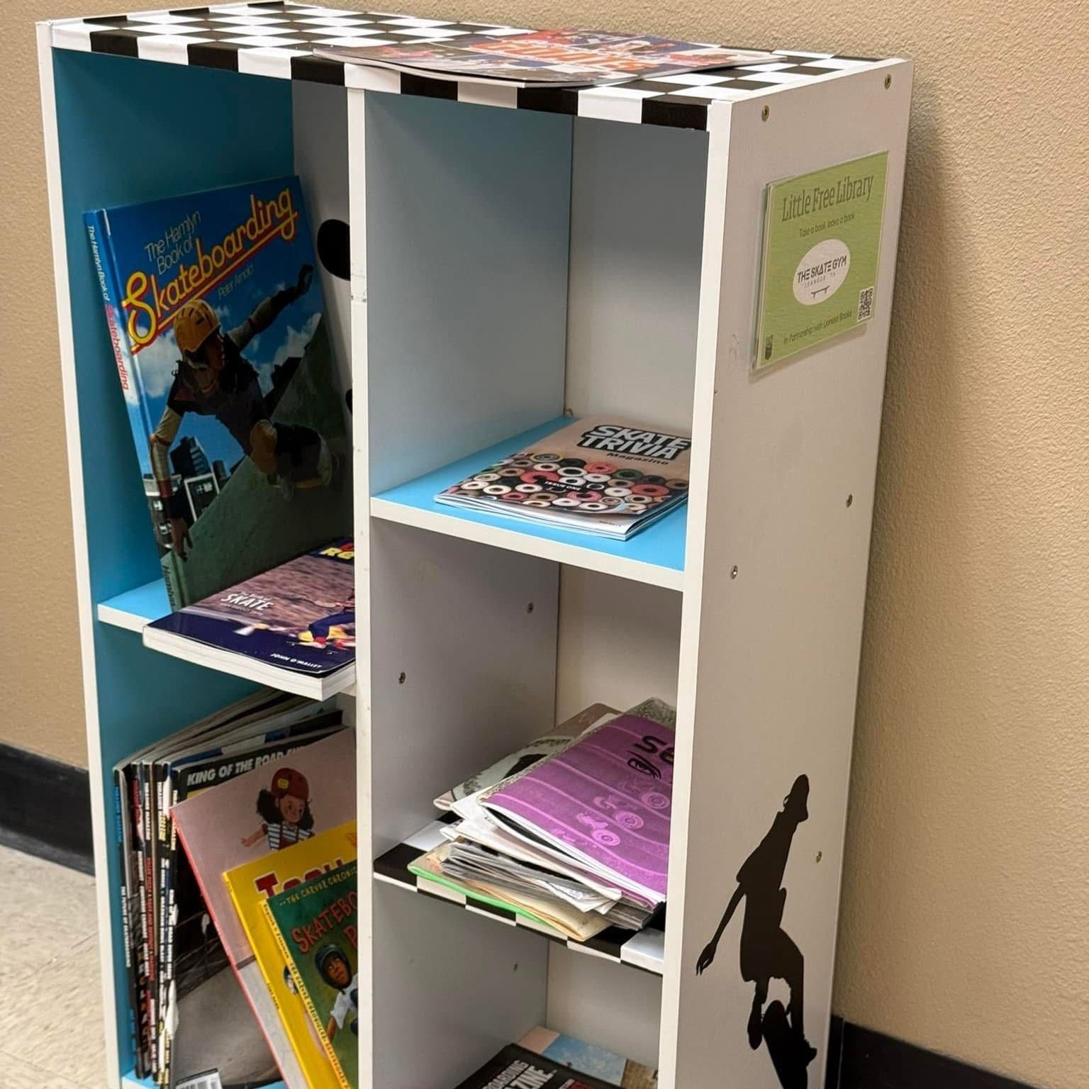 A bookshelf full of free books and a sign for Little Free Library at the top