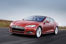 Red Tesla sedan driving on a road.