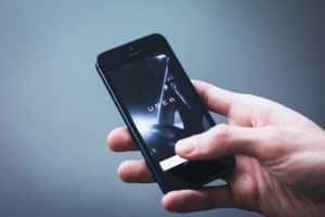 Hand holding a black smartphone displaying the Uber app on a dark background.