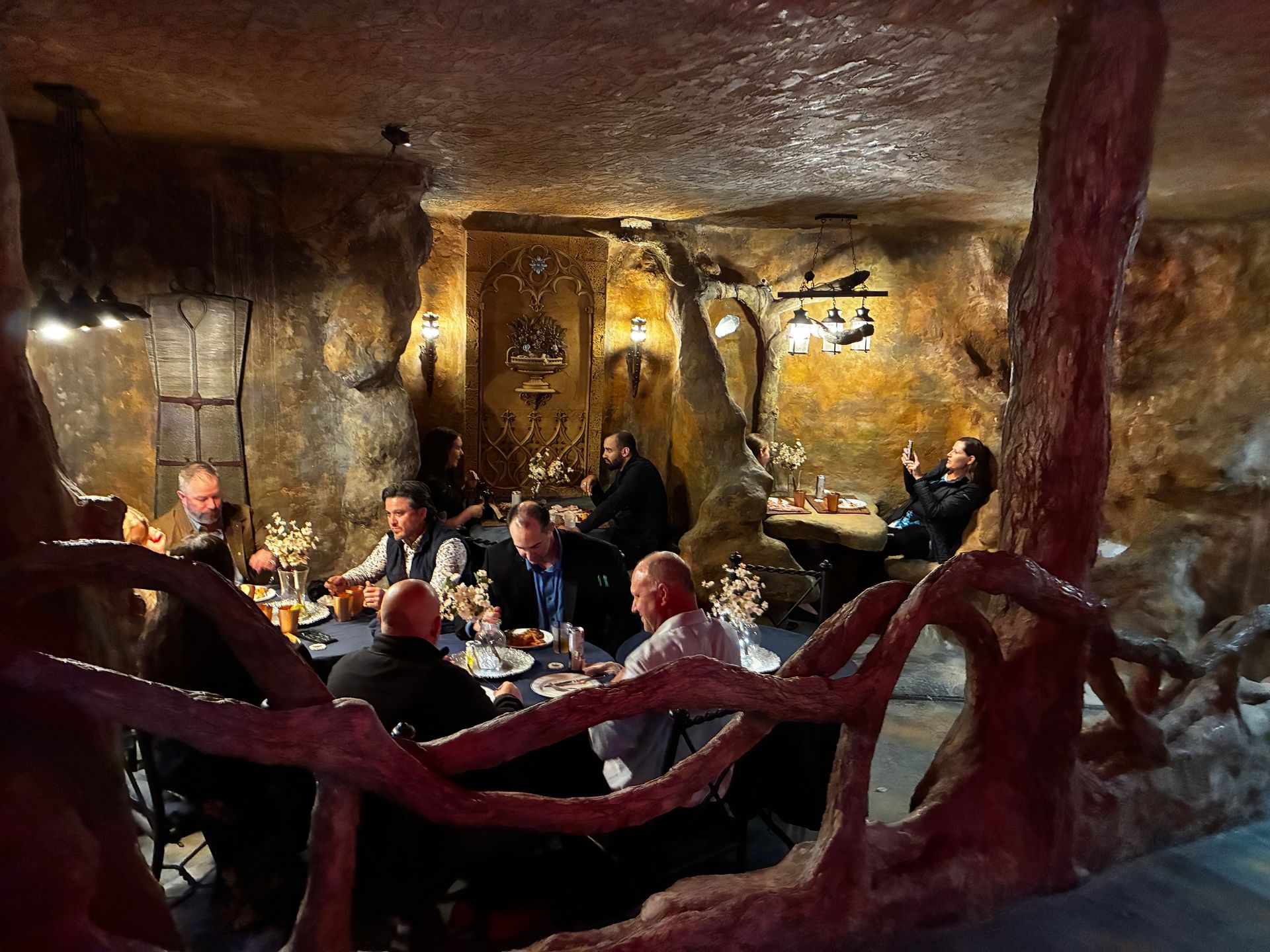 People dining in a rustic cave-like restaurant with warm amber lighting and wooden decor