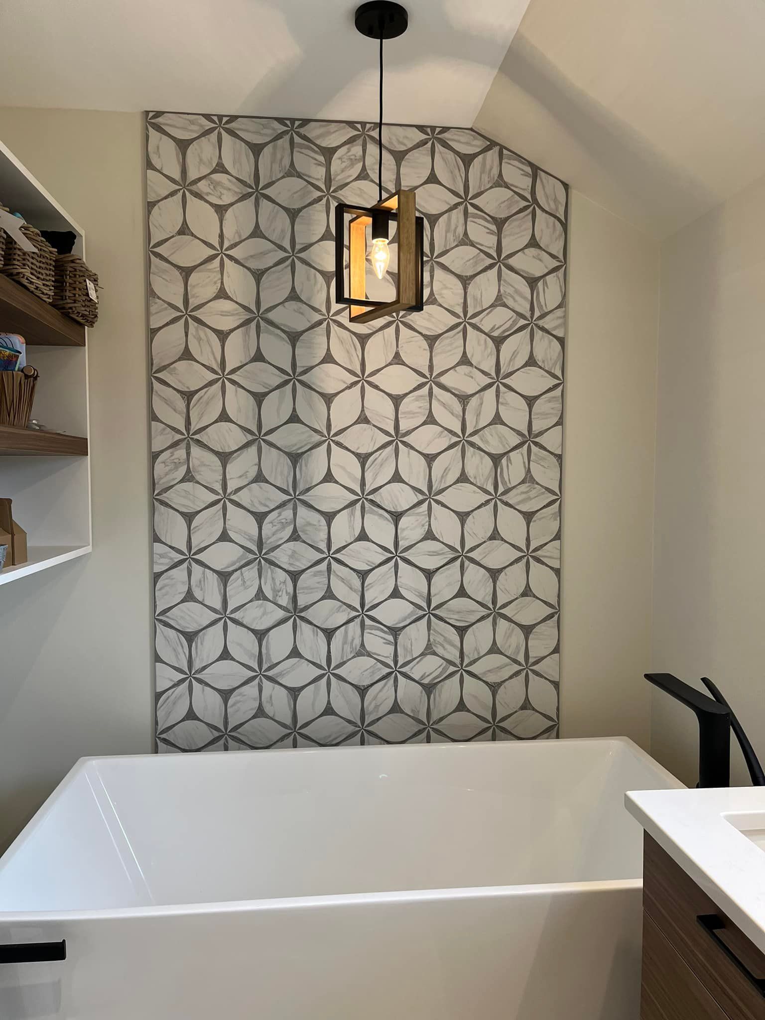 Une baignoire avec un mur d'accent en marbre géométrique derrière elle, agrémenté d'une suspension lumineuse.