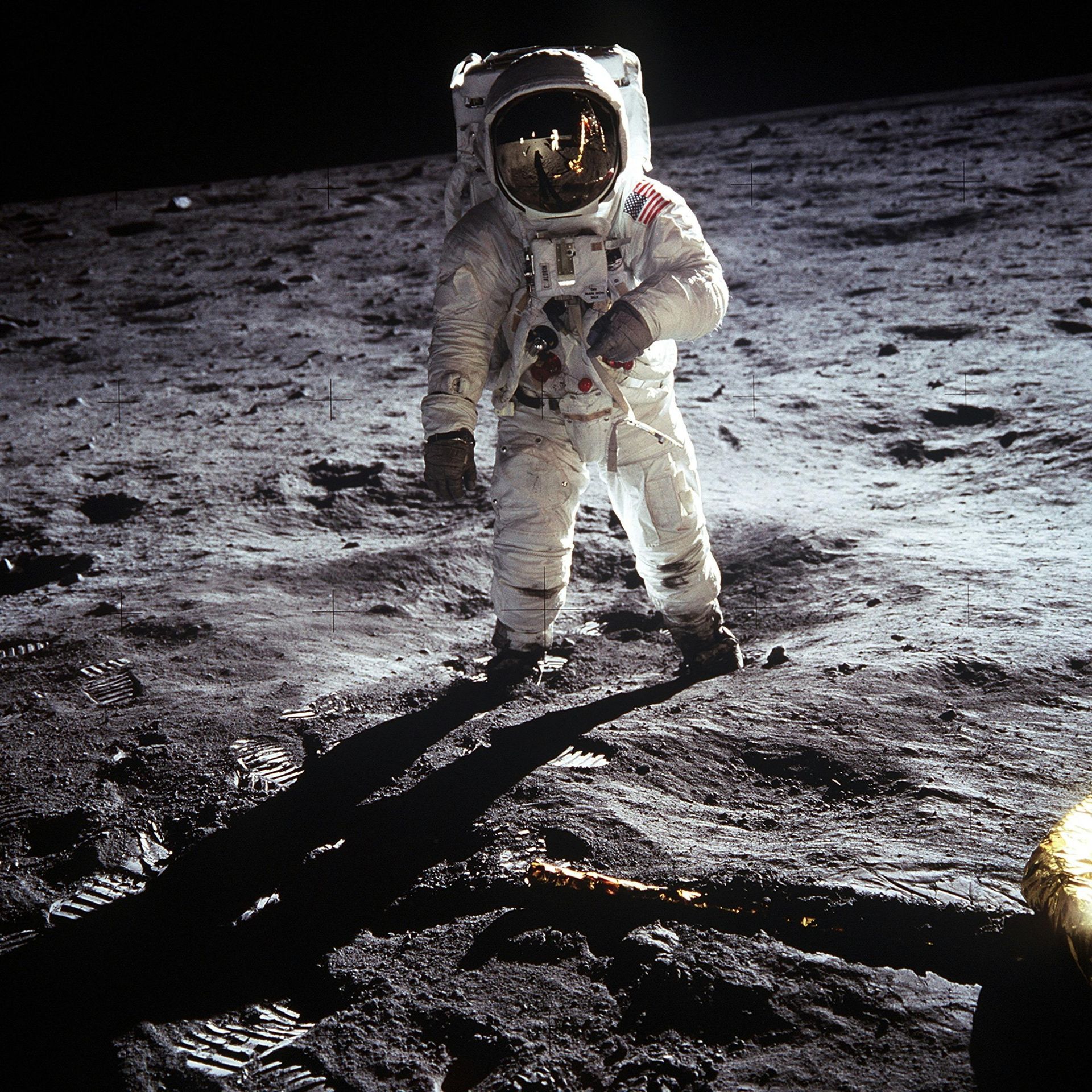 Astronaut in white suit standing on the moon’s rocky surface with a dark sky behind him