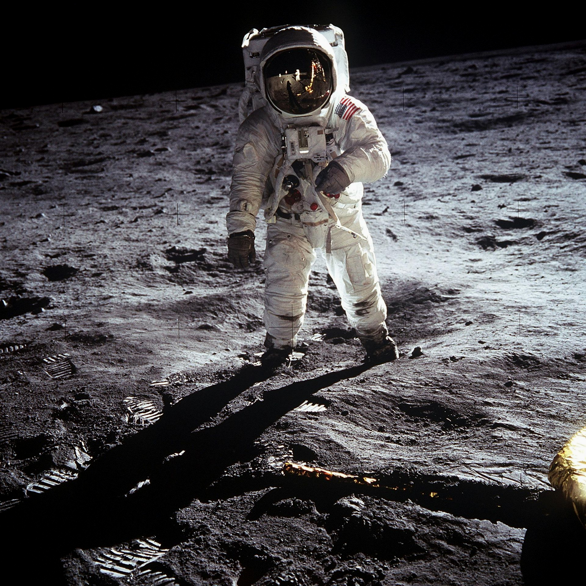 Astronaut in a white spacesuit standing on the moon’s rocky surface under a dark sky