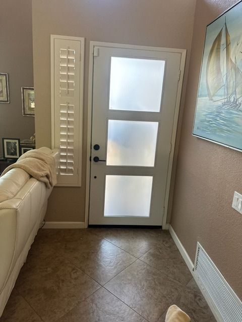 White front door with frosted glass panels; beige tile entryway.