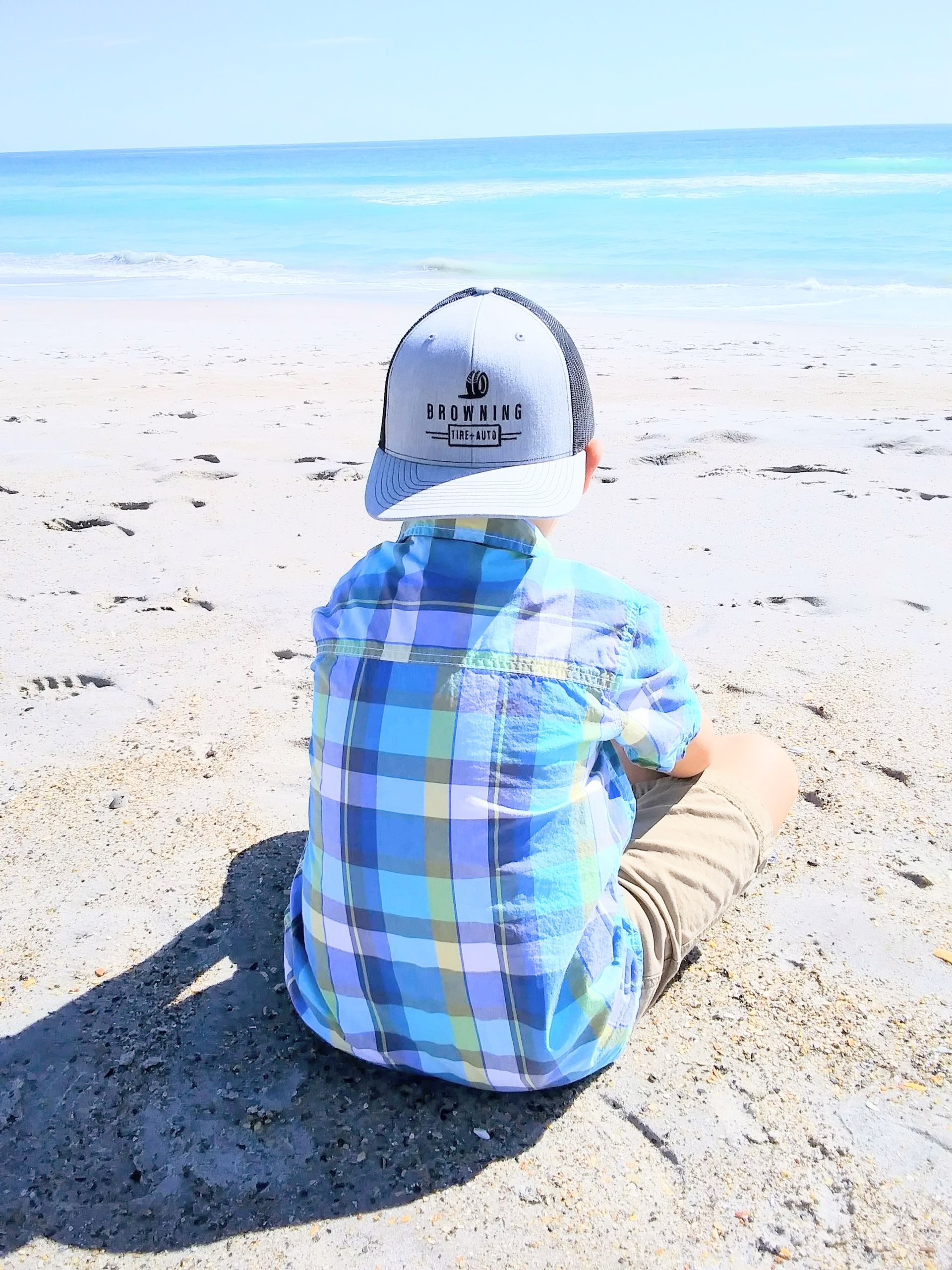 Boy in a Hat Sitting on a Sandy Beach | Browning Tire & Auto
