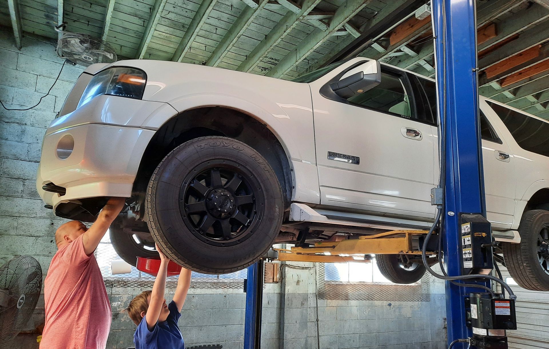Shop Owner and Kid Working Under a White Truck| Browning Tire & Auto