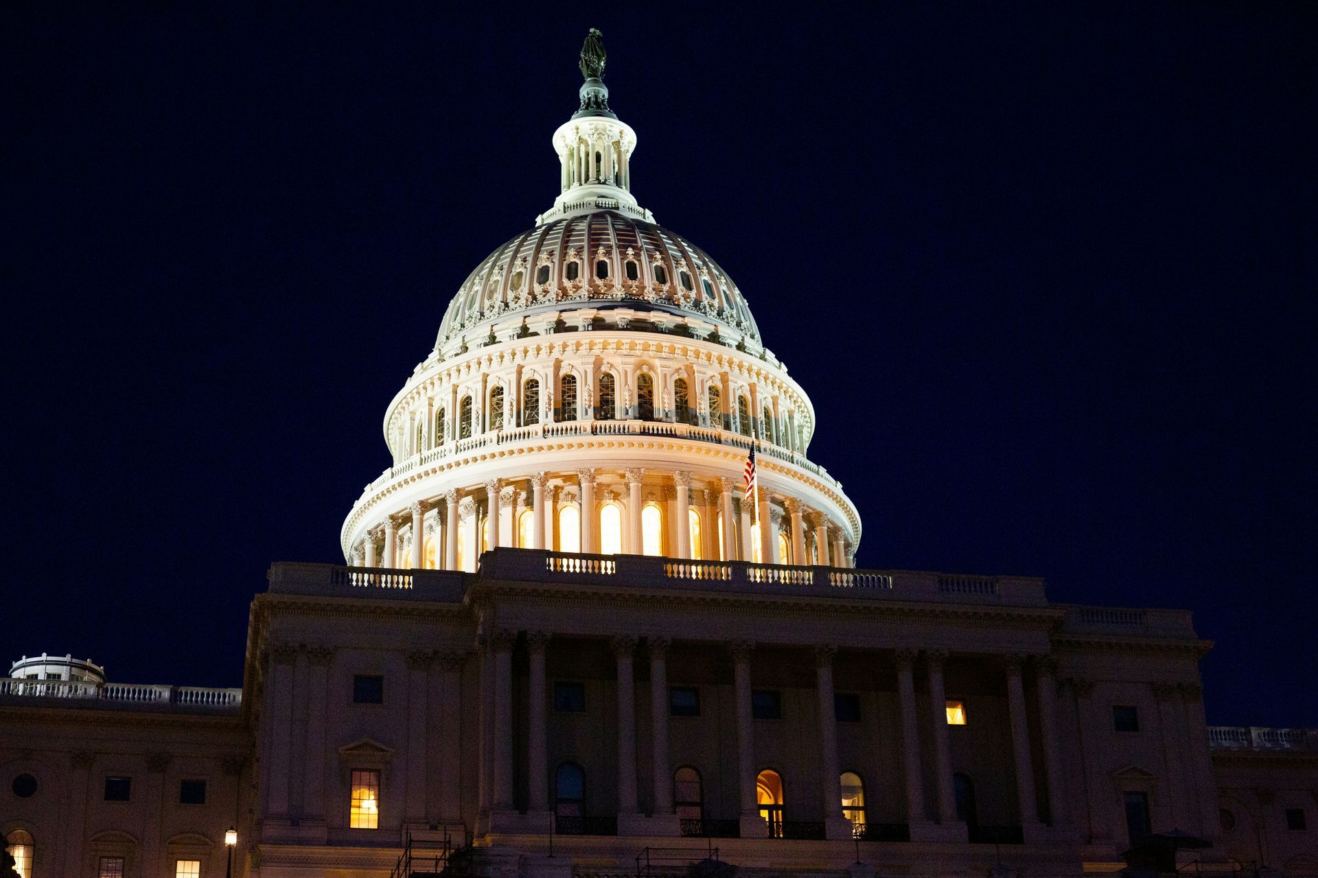 U.S. Capitol dome illuminated at night against a dark sky