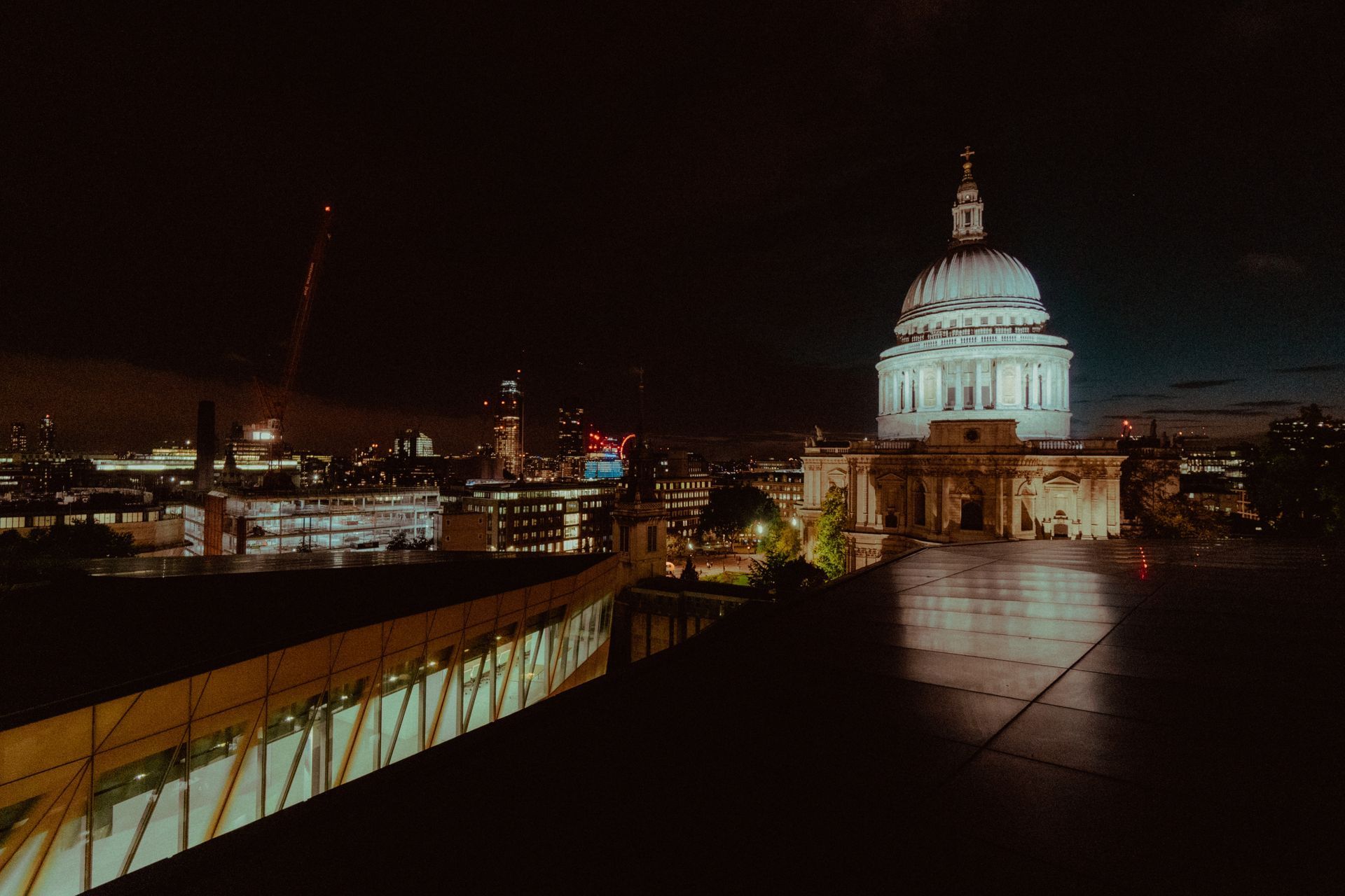 Night view of St. Paul’s Cathedral glowing over the Thames, with city lights and a dark skyline.