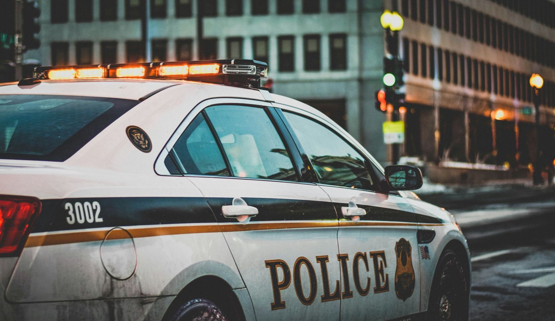 Police car with flashing lights parked on a city street at dusk