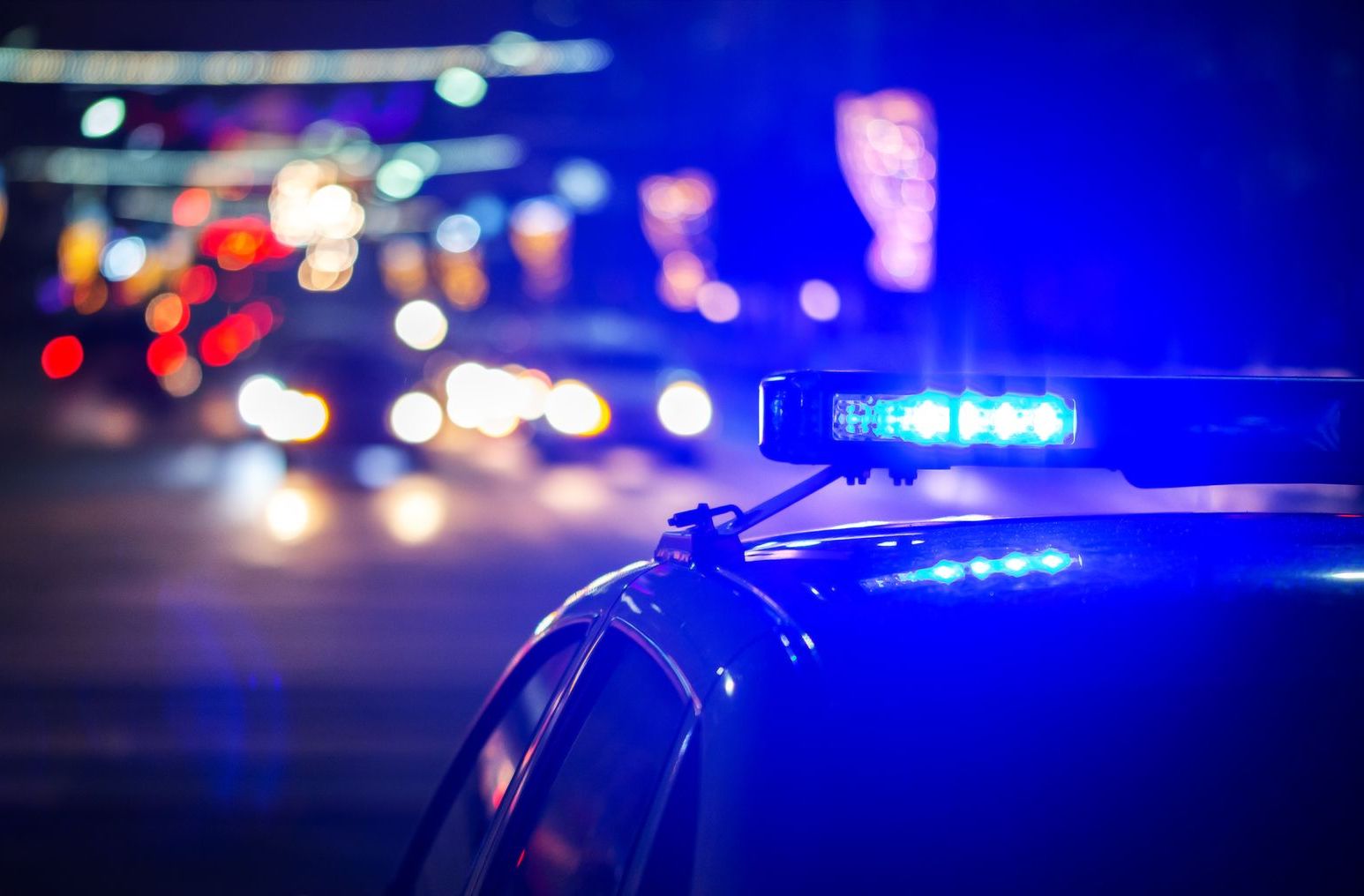 Police car with flashing blue lights on a city street at night
