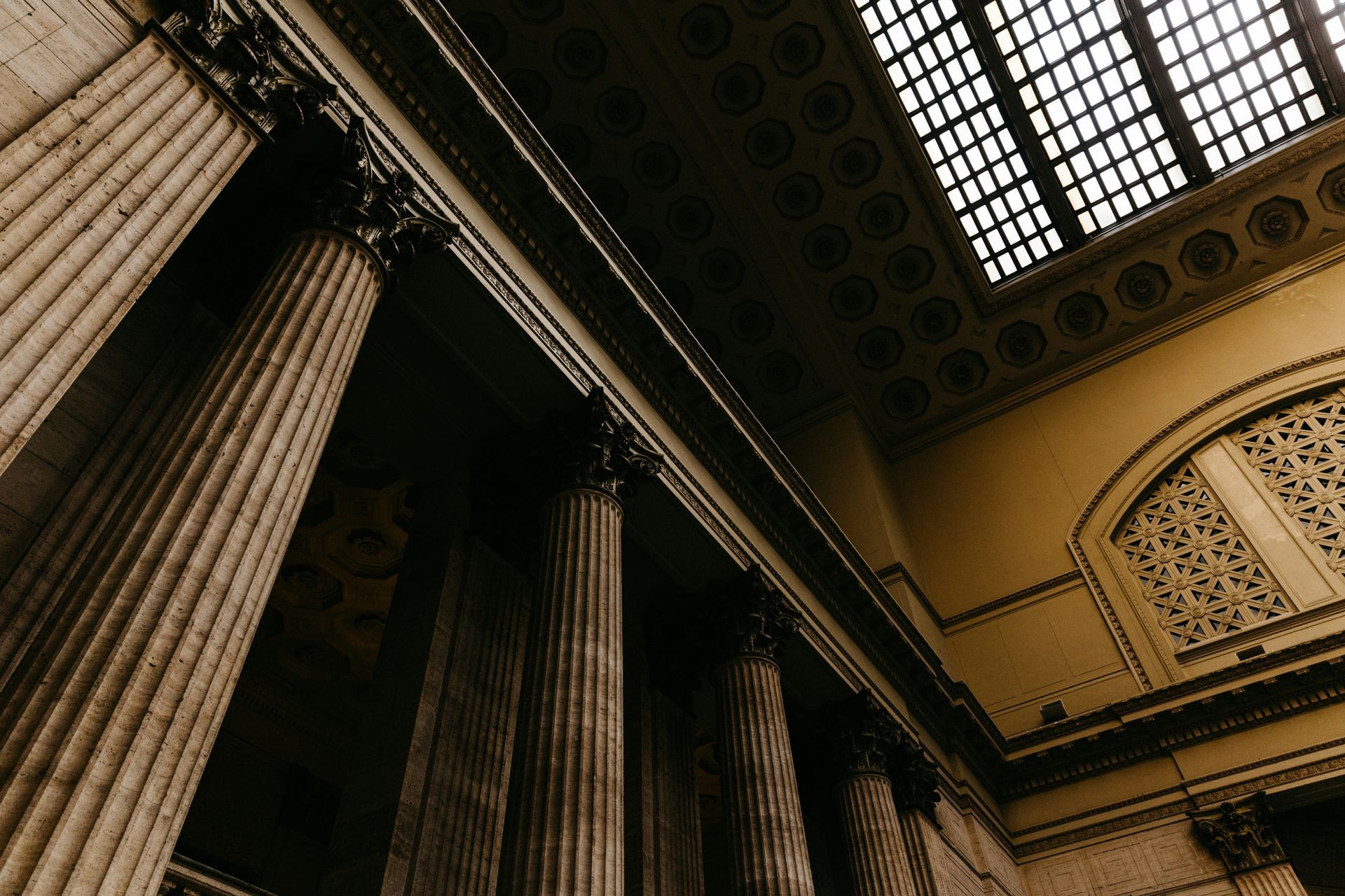 Low-angle view of ornate stone columns and patterned ceiling in a grand interior hall