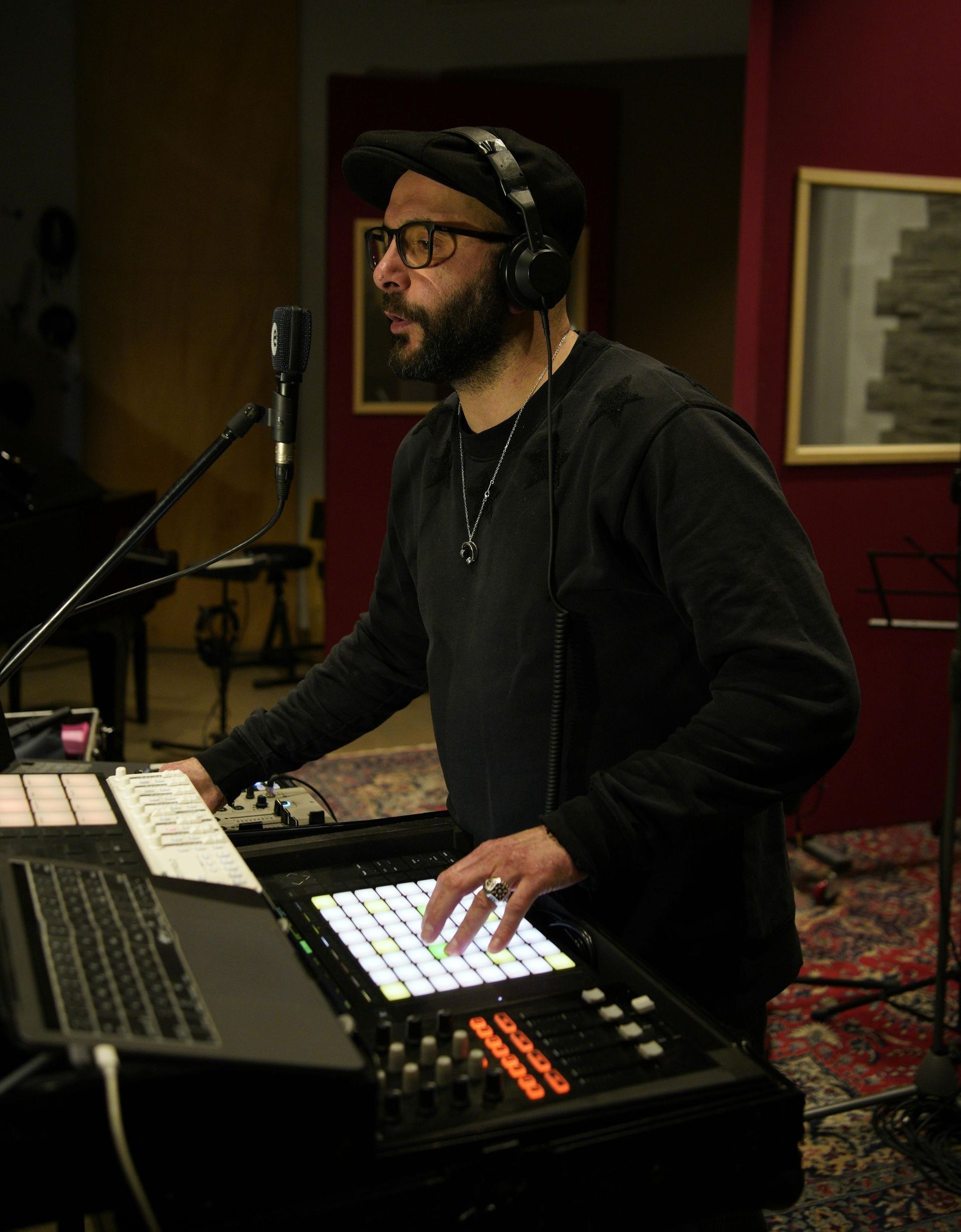 Man wearing headphones operates music equipment in a recording studio.