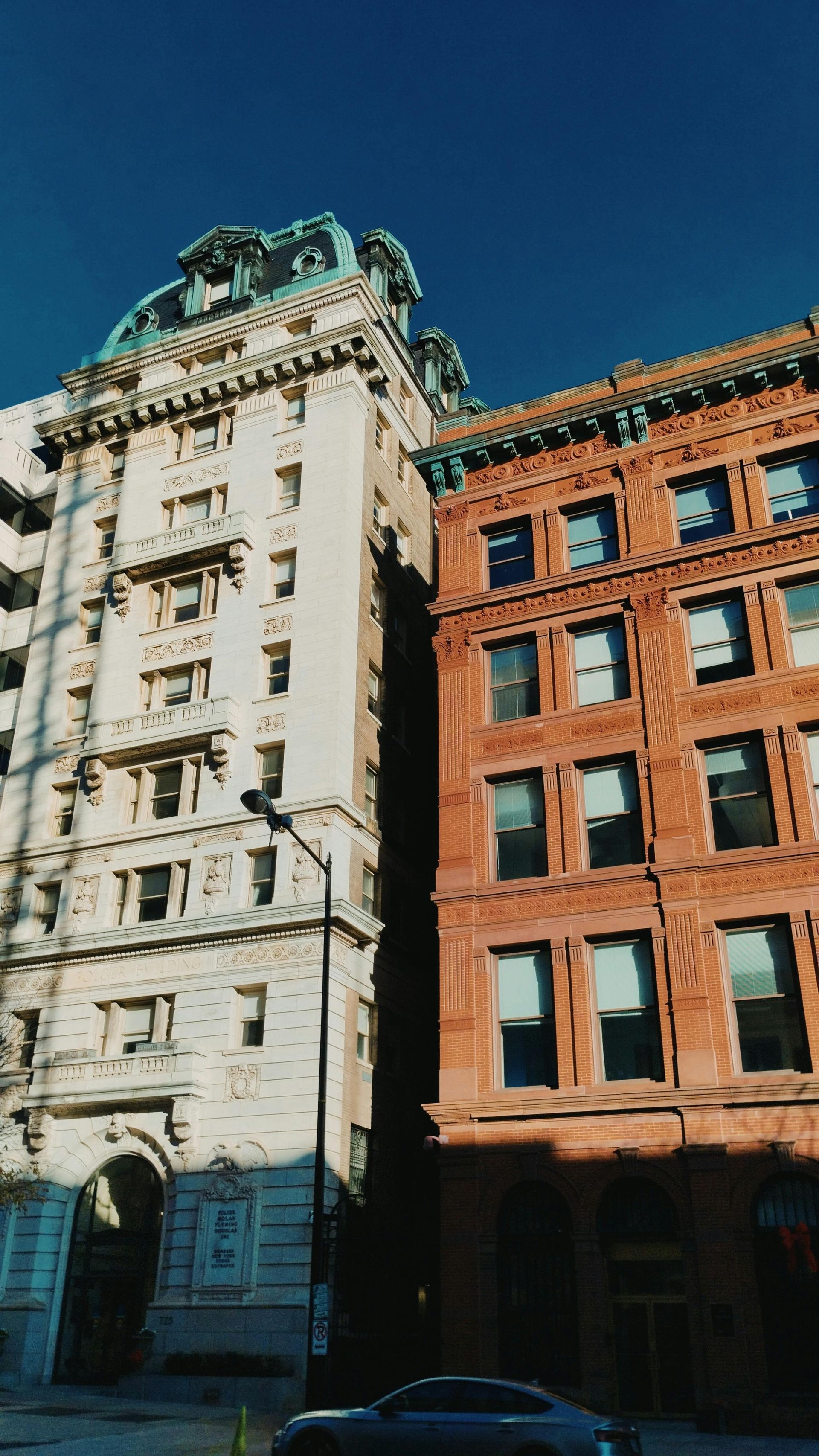 Sunlit historic buildings with white and red brick facades against a deep blue sky