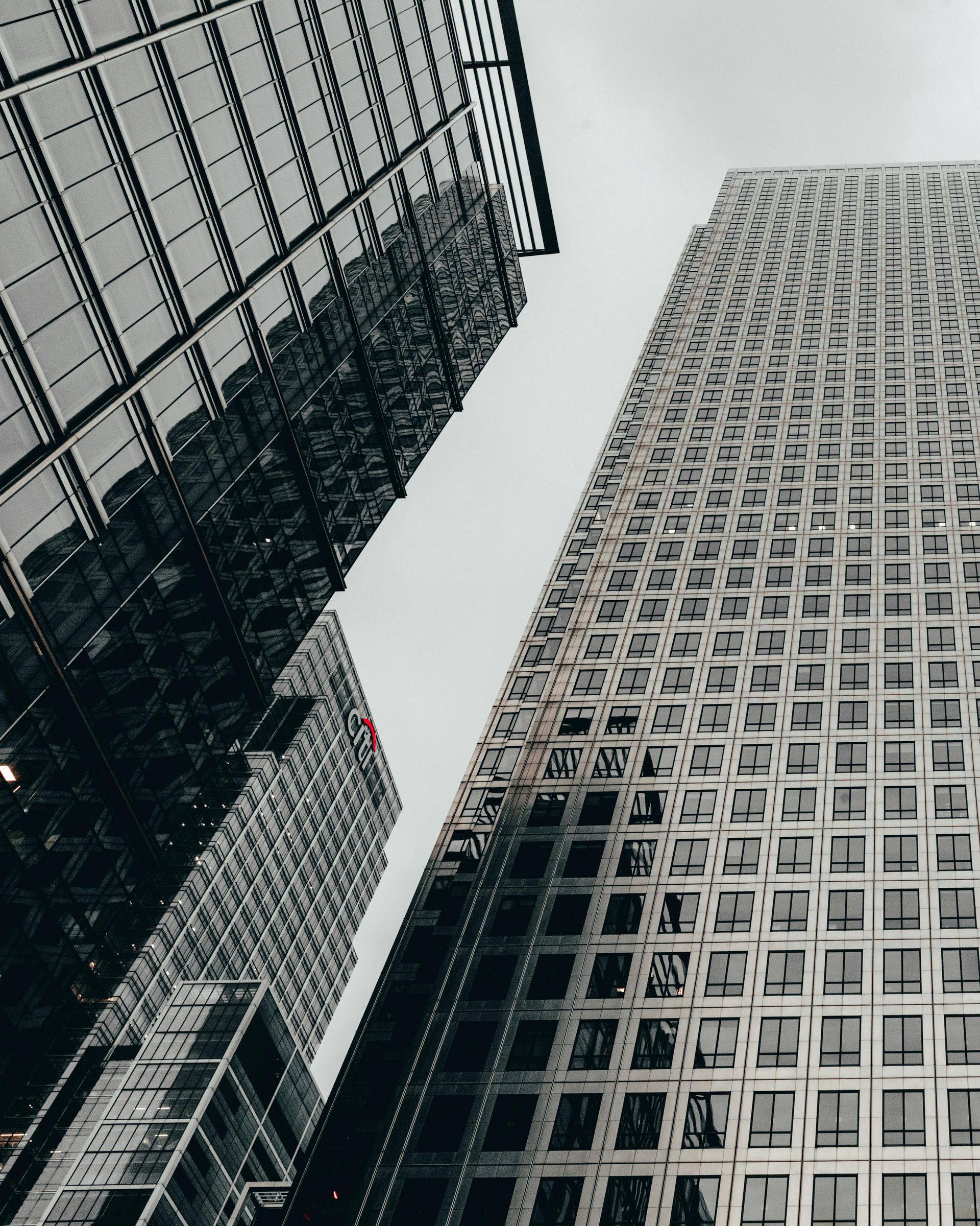 Two tall gray skyscrapers viewed from below against a cloudy sky