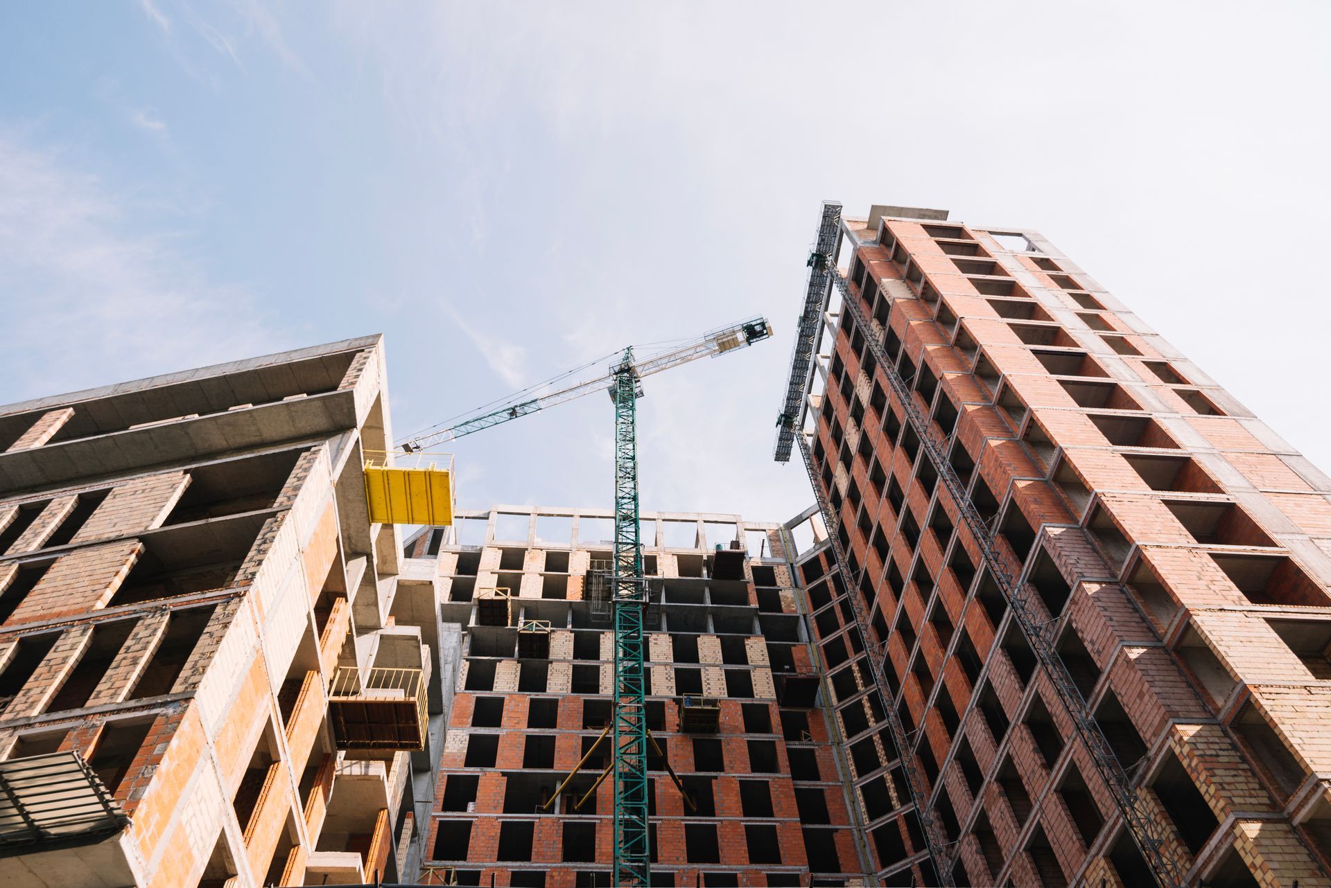 Construction site with two unfinished high-rise buildings and a crane against the sky