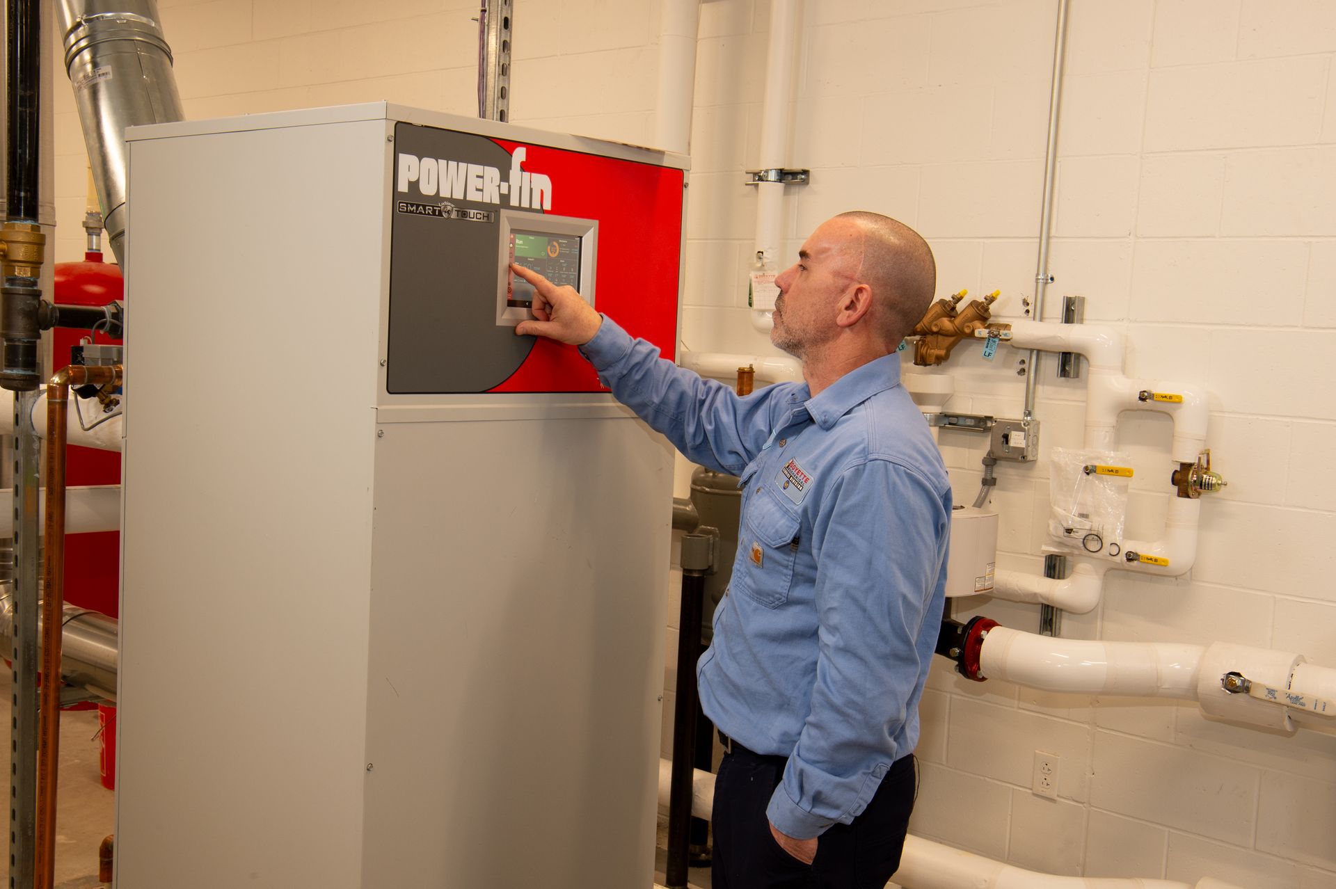 Man adjusting controls on a gray PowerFlex cabinet in a utility room