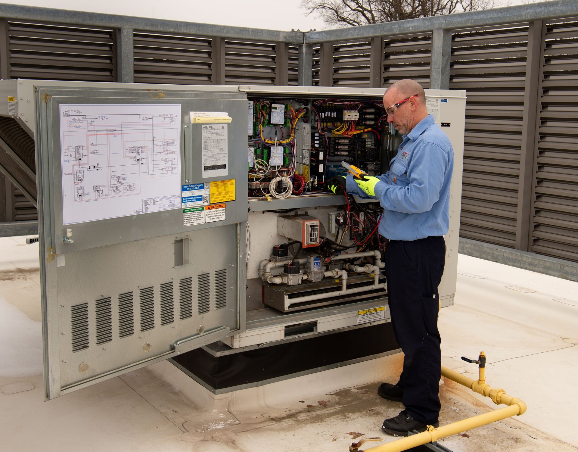 Technician inspecting an open electrical control cabinet outdoors