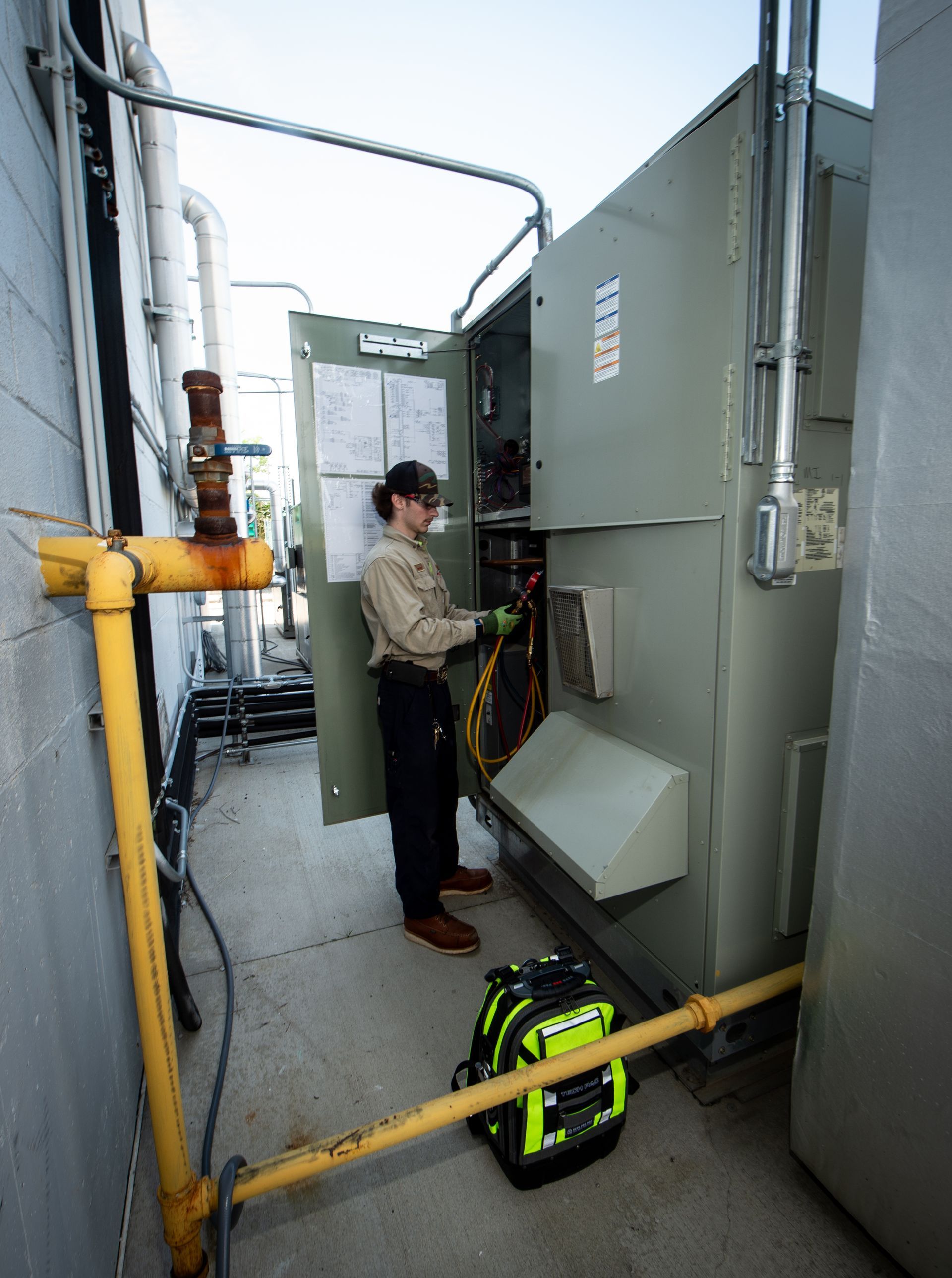Technician inspecting boiler piping and valves in a mechanical room