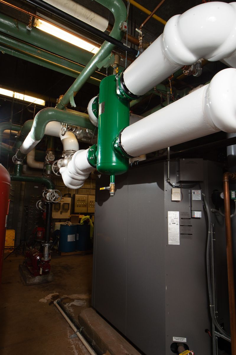 Green pump connected to white pipes and a gray industrial unit.