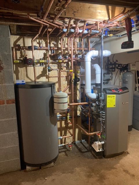 Plumbing and heating system with copper pipes, two water tanks, and a boiler in a basement.