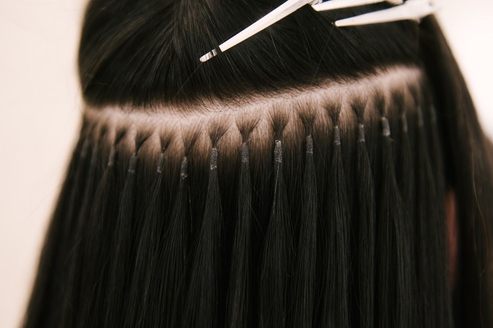 Close-up of black hair extensions being sewn into a braided parting