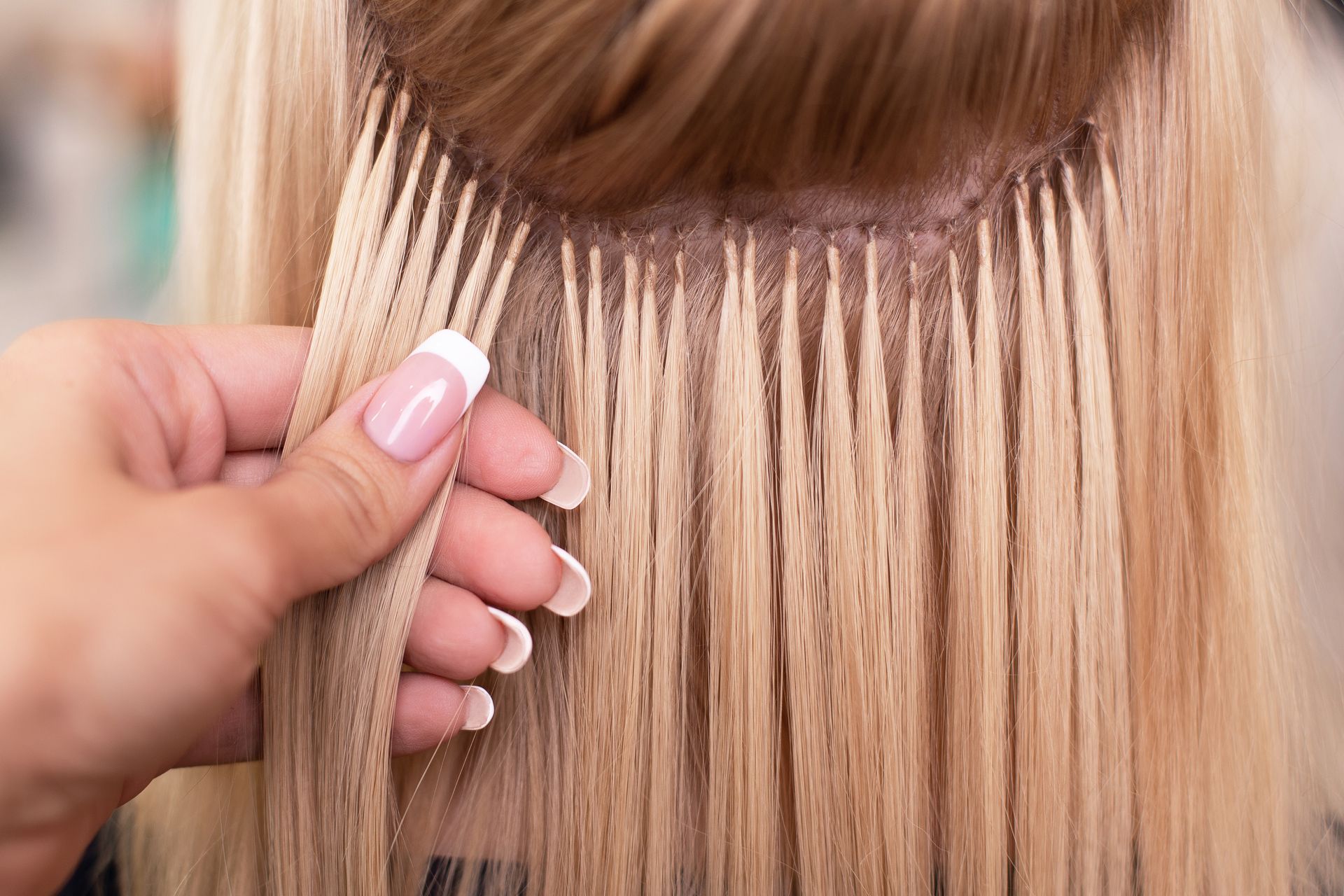 Hand weaving blonde hair extensions into long blonde hair close-up