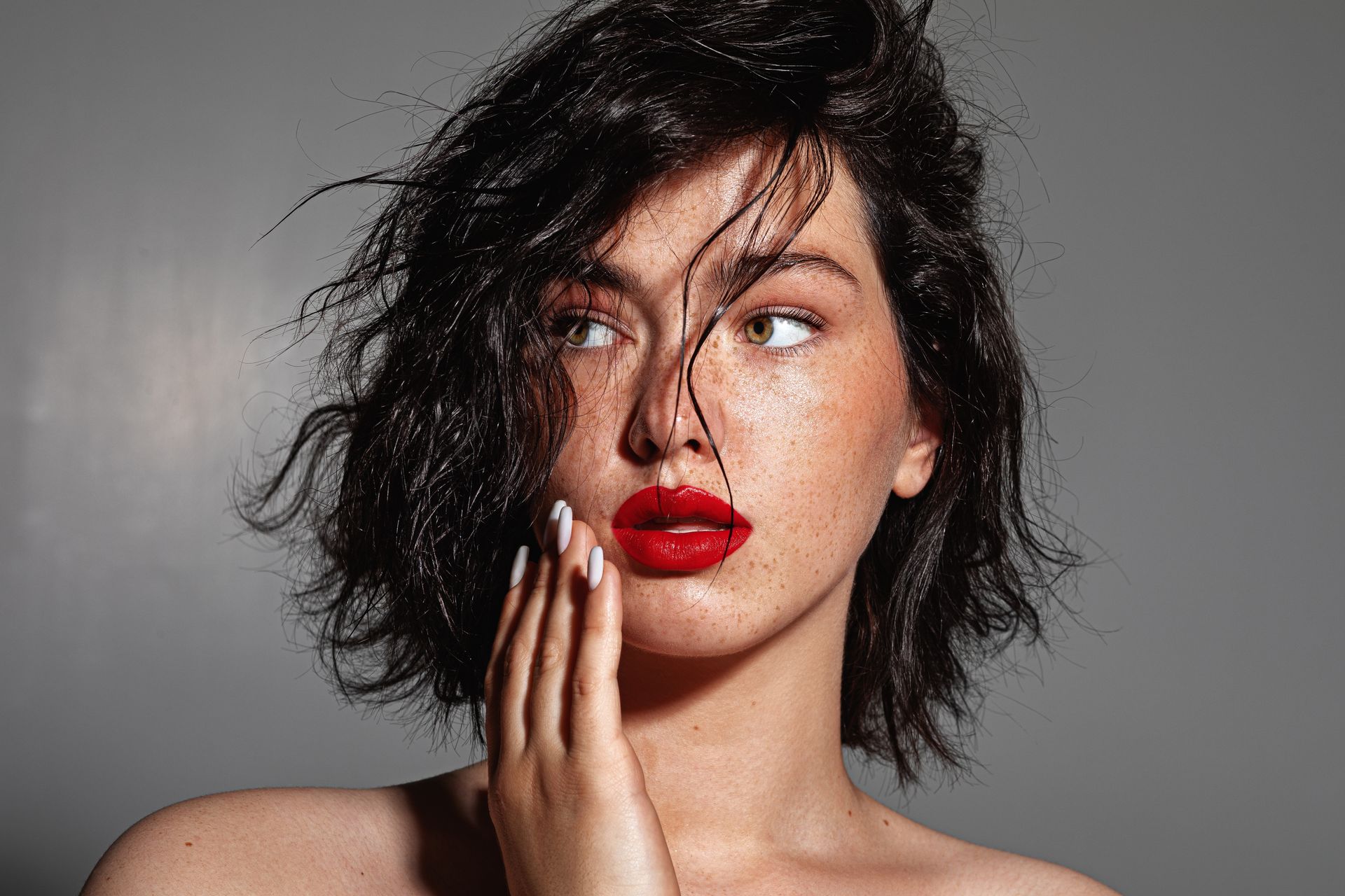 A woman is touching her face with her hands and smiling.