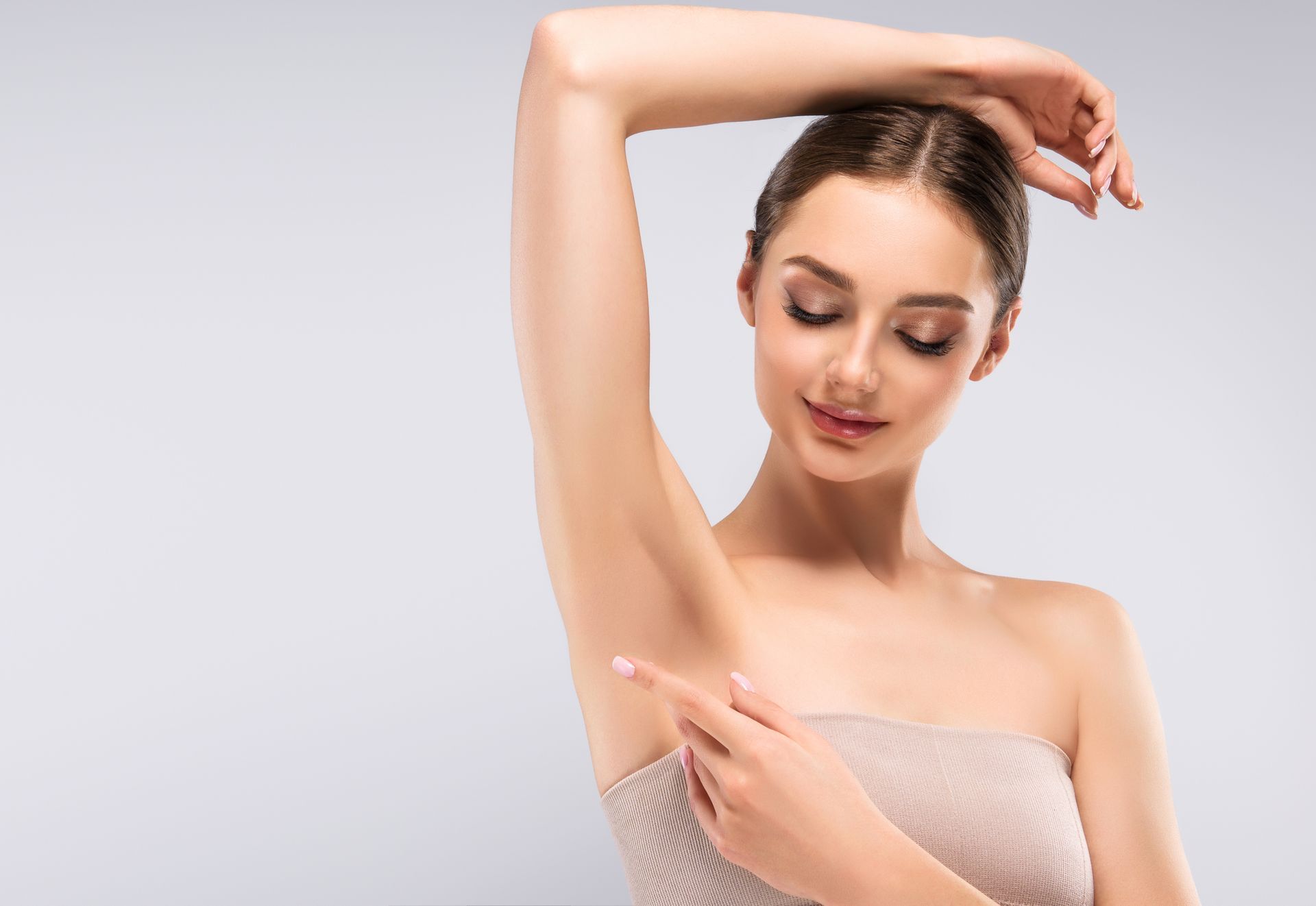 A woman is pointing at her armpit with her finger.
