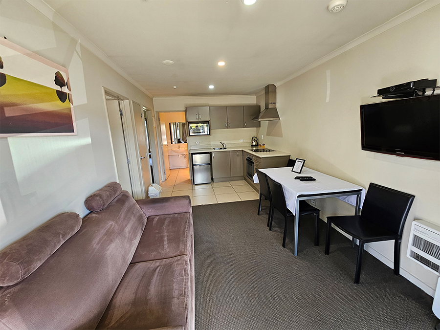 A living room with a couch , table , chairs and a flat screen tv.