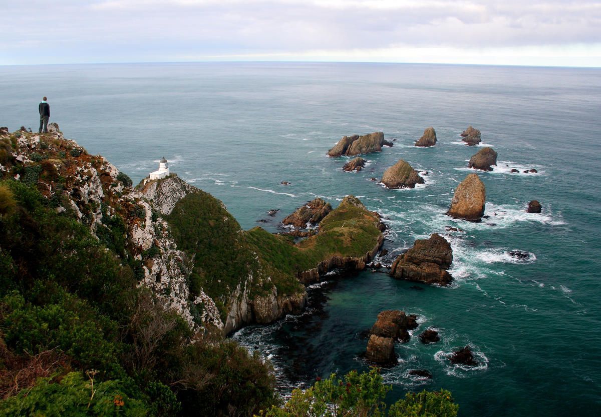 A man standing on top of a cliff overlooking the ocean