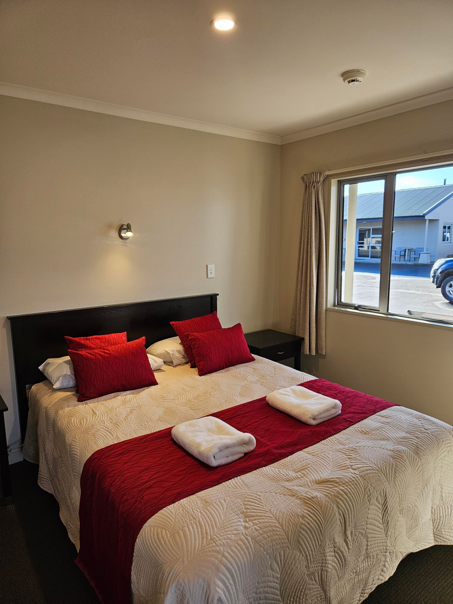 A hotel room with a king size bed and a window.