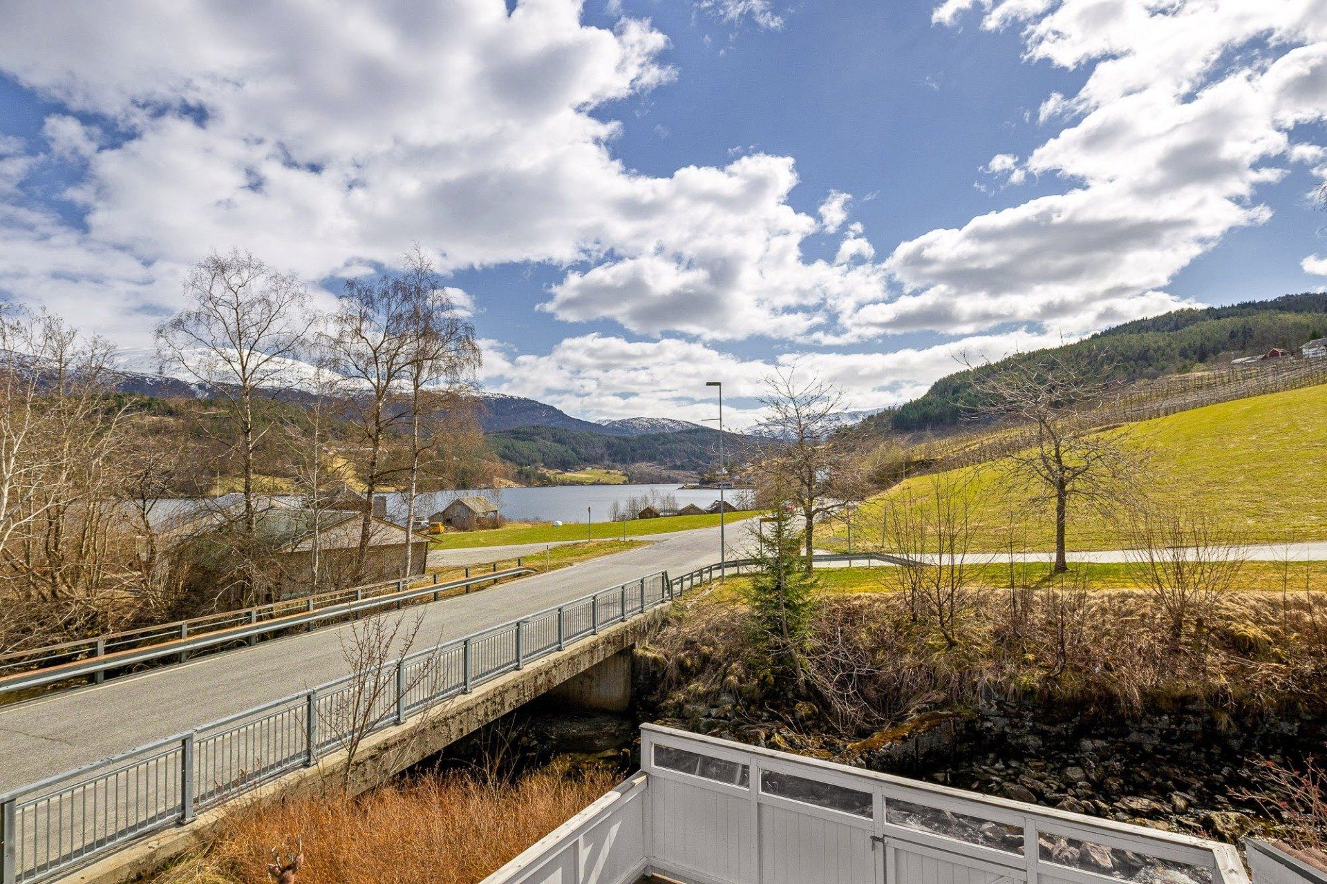 Railroad bridge over a river in a rural valley under a cloudy sky