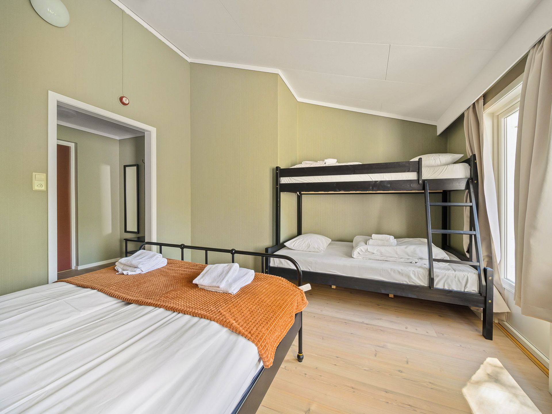 Bedroom with twin bed, bunk bed, light green walls, and large windows with curtains