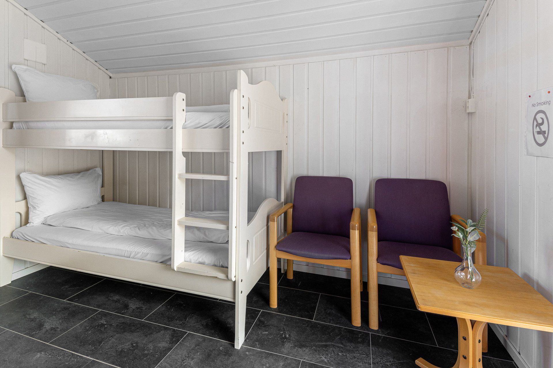 White room with bunk bed, purple chairs, and a small wooden table