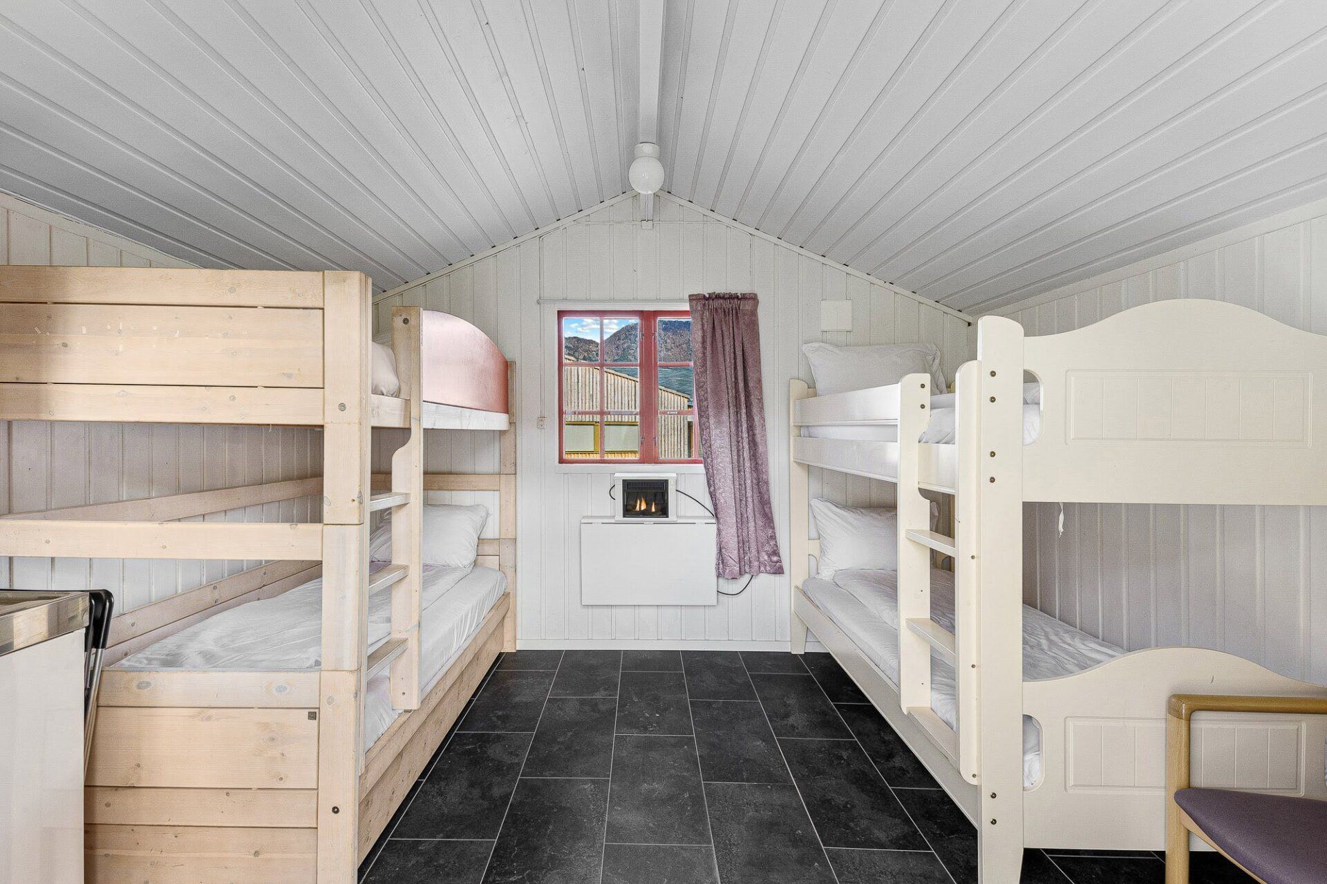 Shared bunk room with white bunk beds, black tile floor, and a small window with curtains.