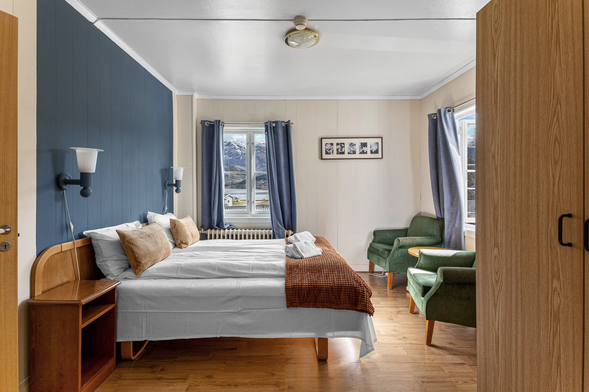Bedroom with a bed, green chair, blue walls, and a window letting in daylight