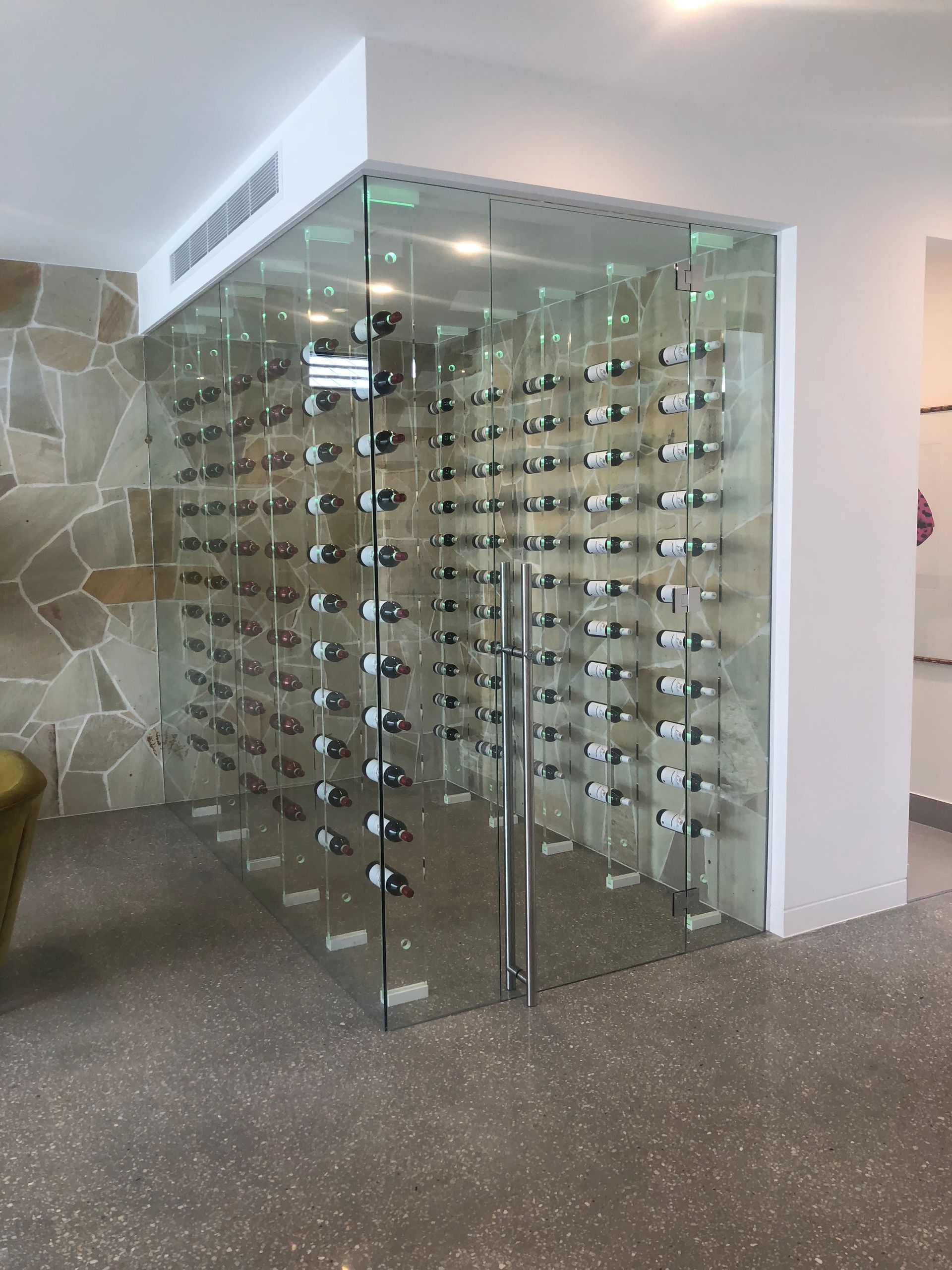 A glass wine cellar filled with lots of wine bottles