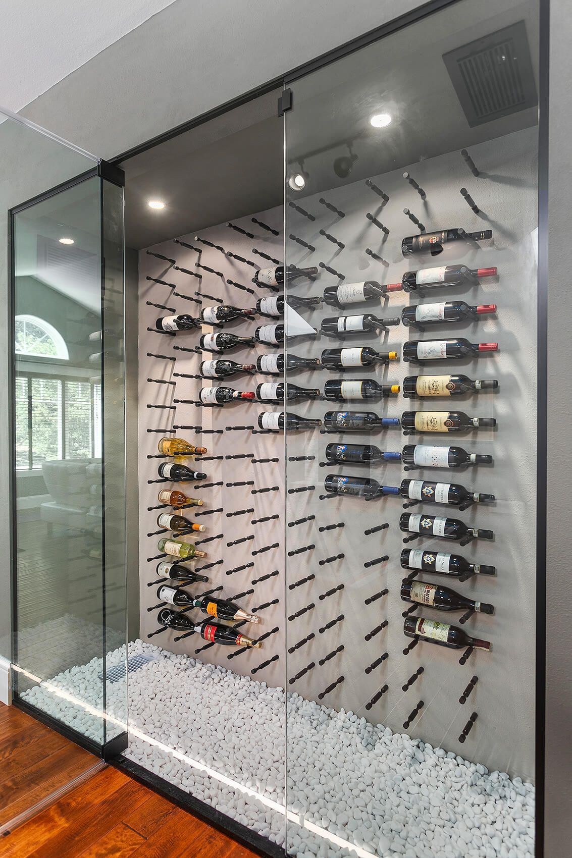 A wine cellar filled with lots of bottles of wine behind a glass wall.