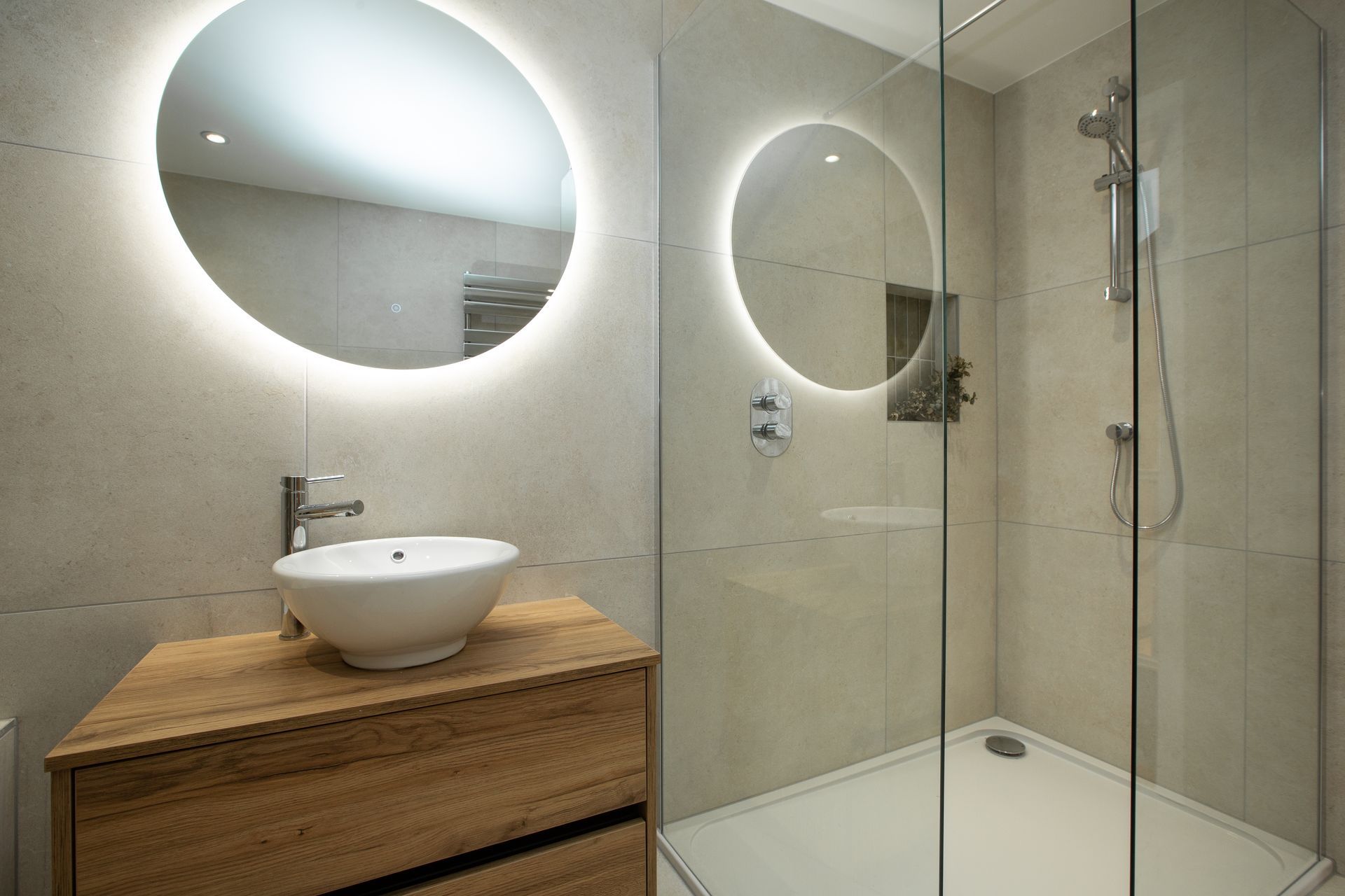 A bathroom with a sink , mirrors and a walk in shower.